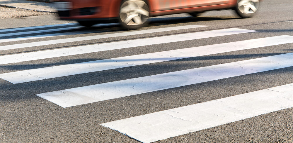 Pedestrian crossing with orange car speeding past