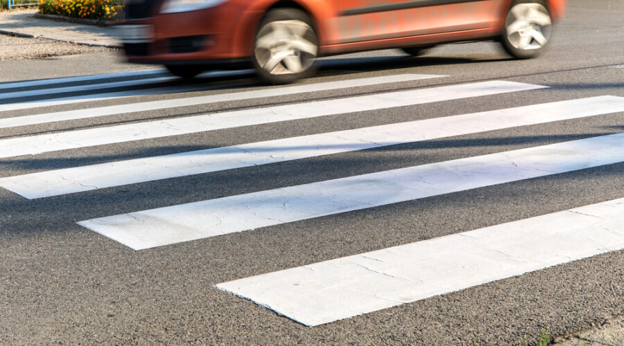 Pedestrian crossing with orange car speeding past