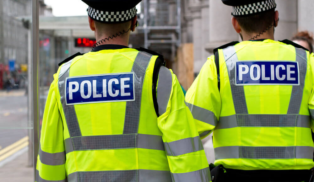 Colour image of two British police officers in hi-visibility jacket patrolling in the city