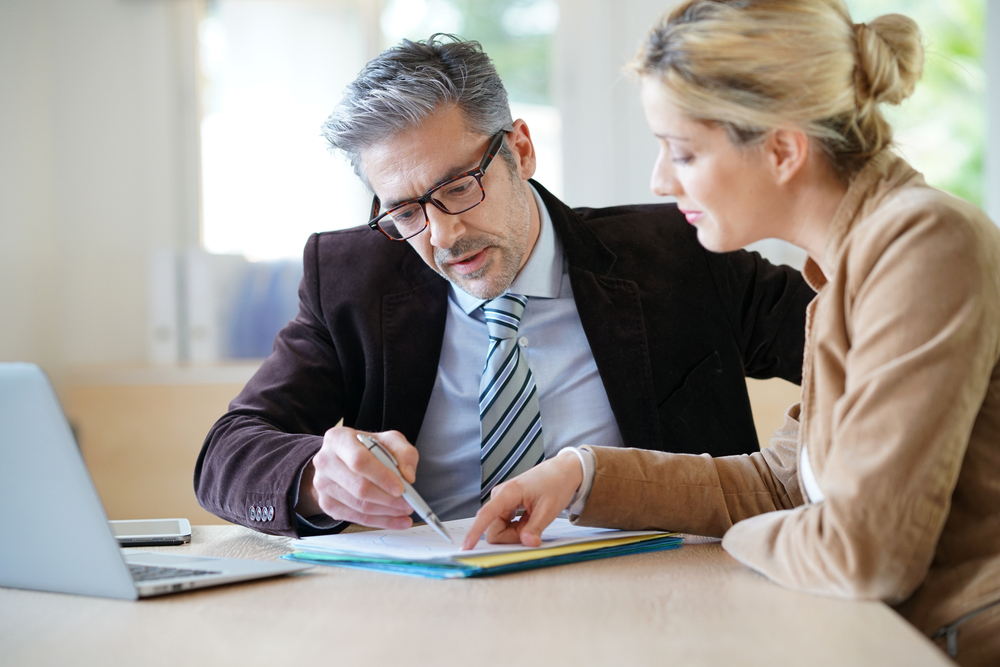 Photograph of woman sat at a wooden table with a laptop, meeting with solicitor for advice