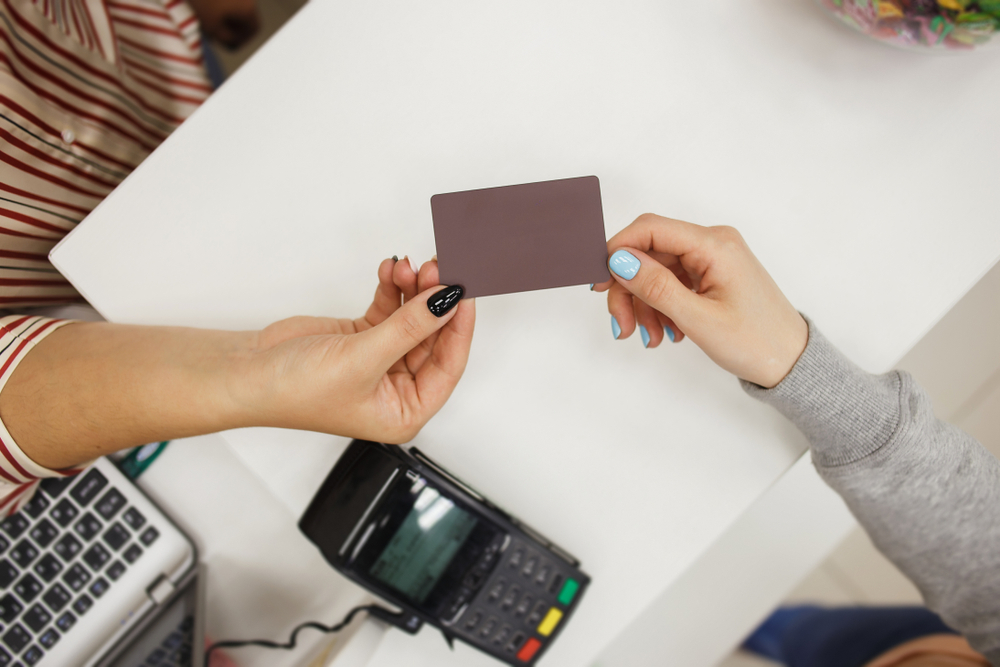 Photograph of female customer handing over loyalty card to woman behind cash register