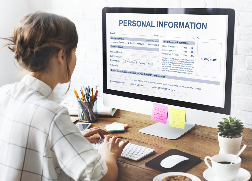 Woman uploading her personal information sat at her desk with her PC