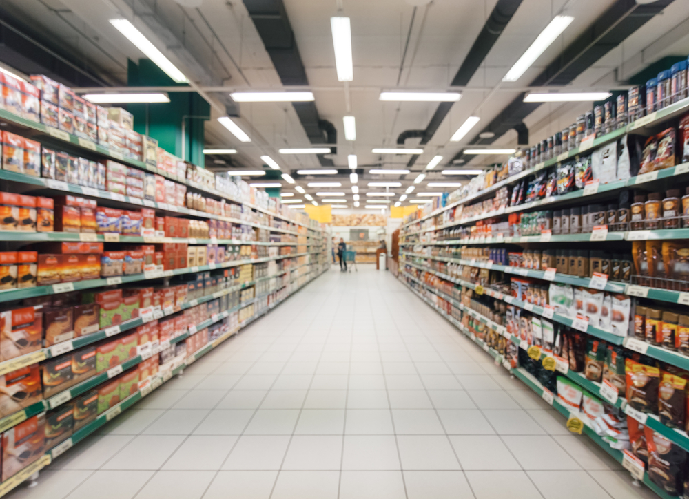 Photograph of a blurred supermarket aisle, with products on the shelves