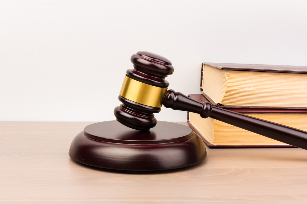 Photograph of a judge gavel next to a pile of law books