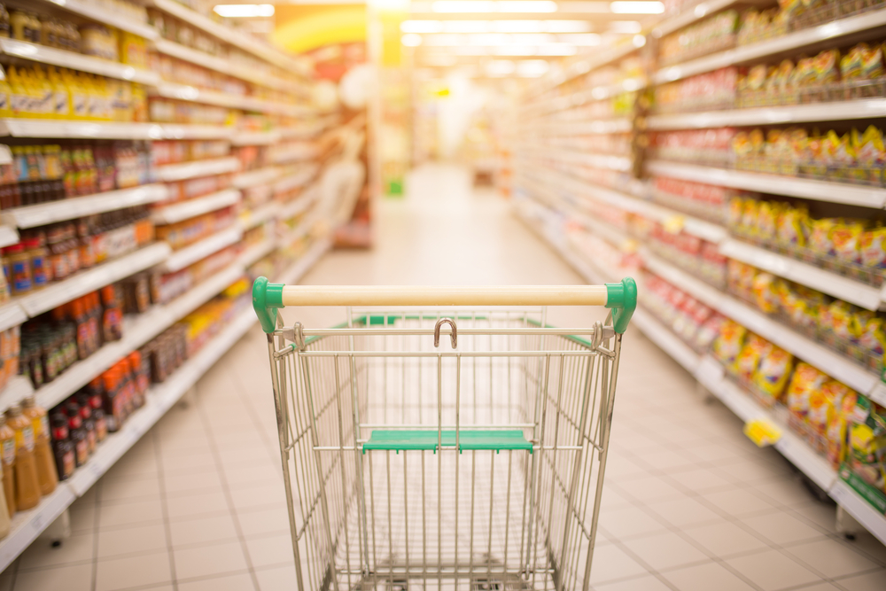 Photograph of an empty green and yellow shopping trolley in the middle of an aisle