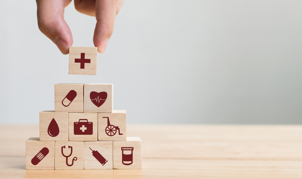 Small wooden building blocks with medical icons on them to represent the different types of insurance