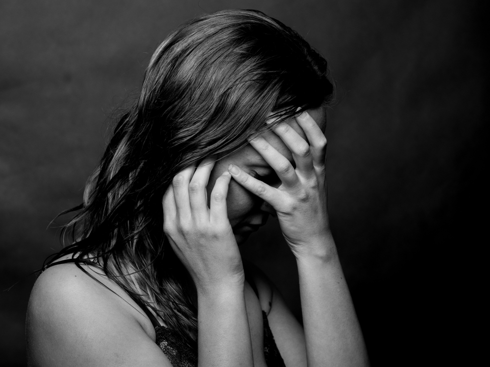 Black and white photograph of a psychological abuse victim covering her face 