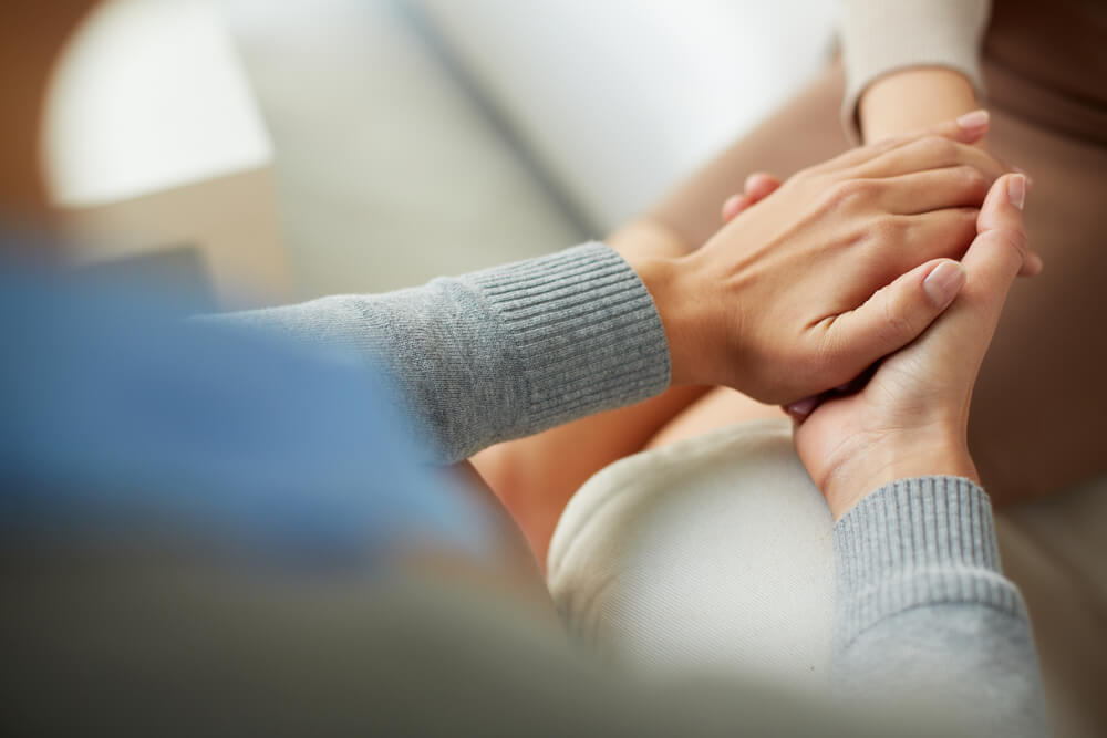 Close-up of two woman holding hands and comforting each other after psychological injury