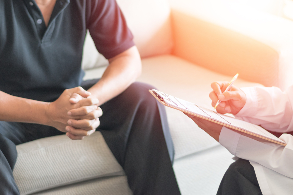 Man speaking with his doctor on a couch about the extent of his psychological injuries