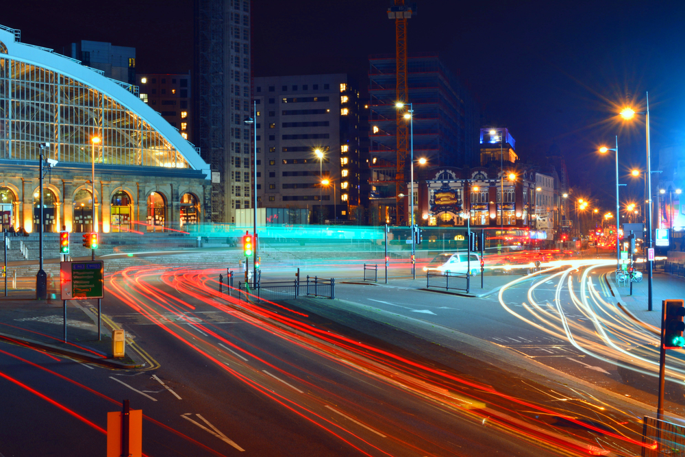 View of Liverpool Lime Street at night with fast, red car lights on the road