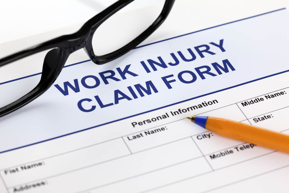 Close-up of a work injury claim form next to a pair of glasses and a pen