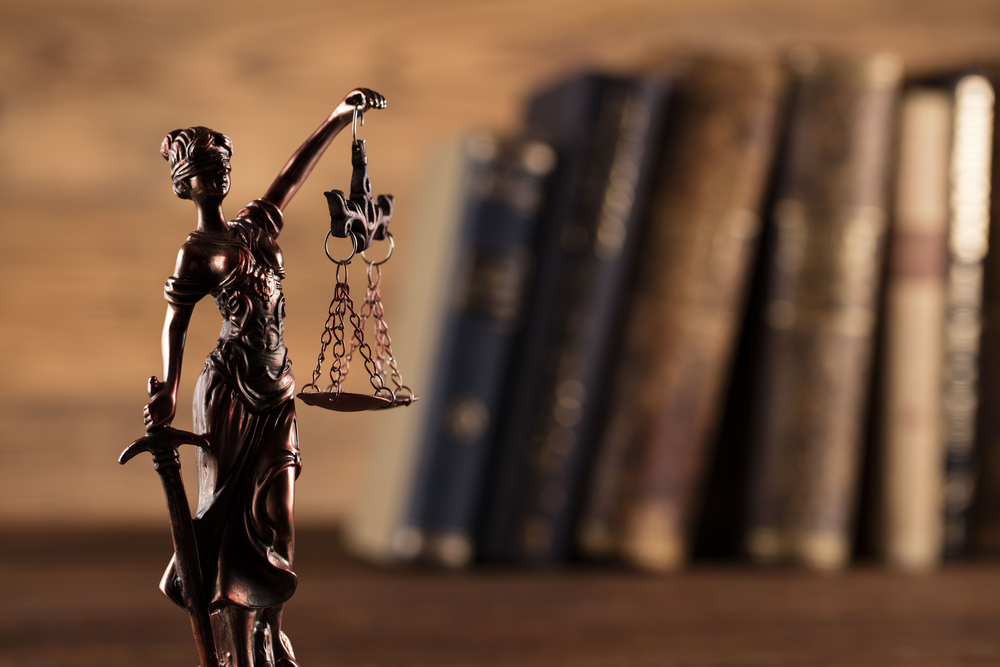 Statue of justice against a blurred background of books