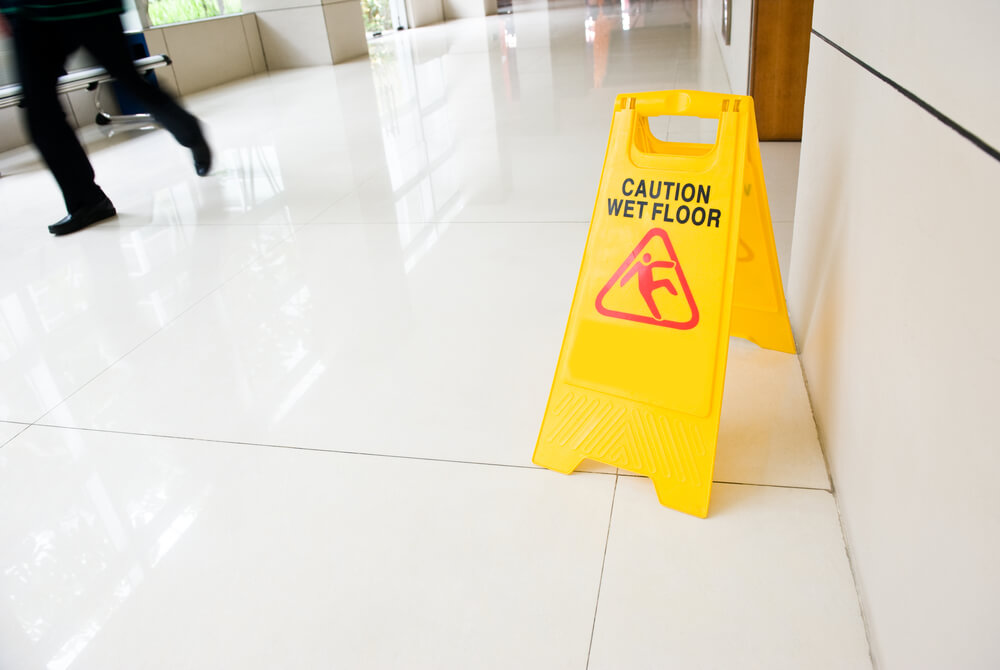 Photograph of a wet floor sign and a man falling over partly off screen