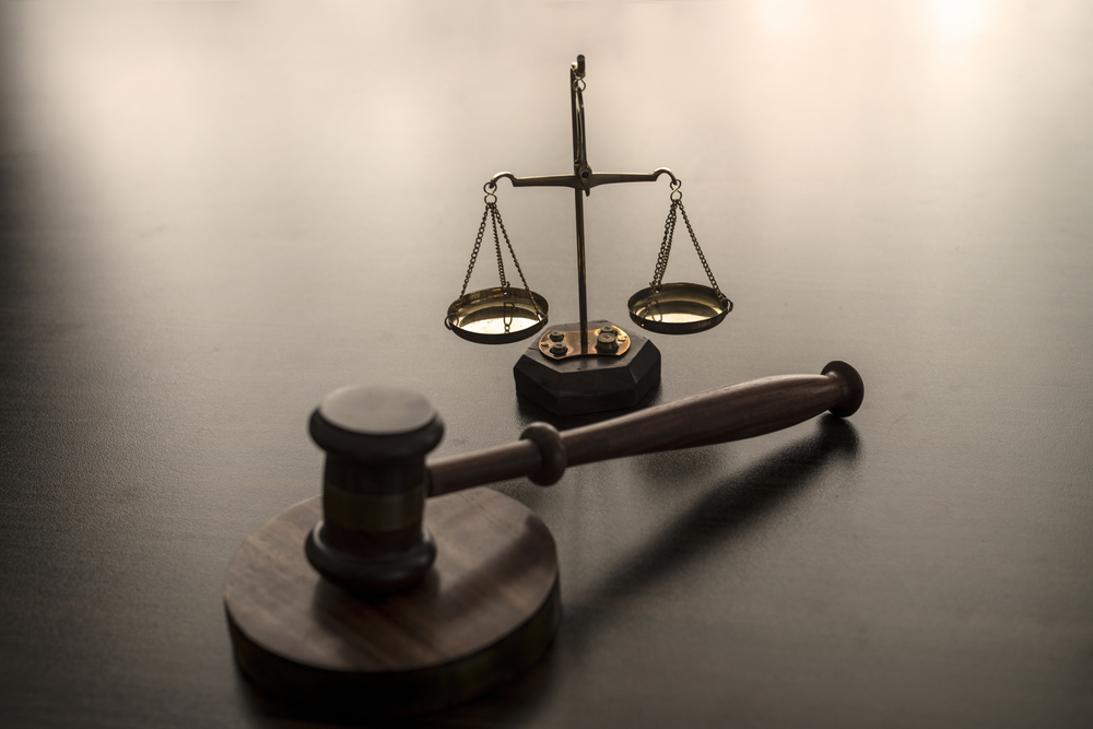 Dimly lit gavel and statue of justice scales on a table