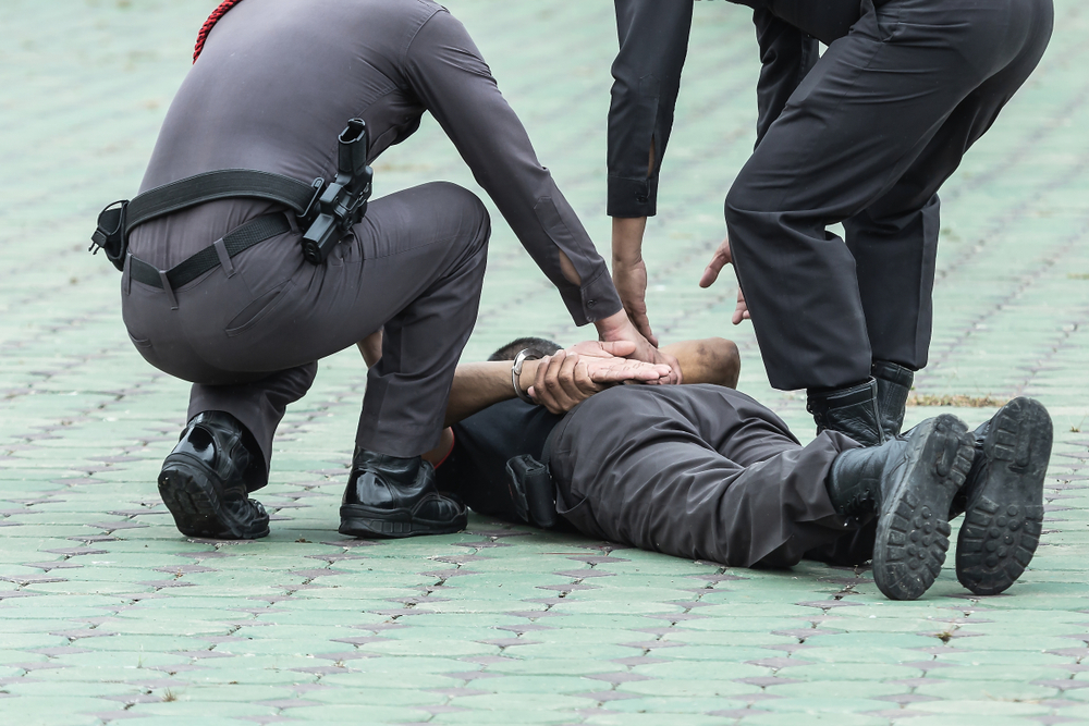 Two policeman arresting young black man who is pinned on the floor