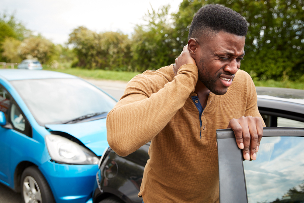 Photograph of a man with whiplash injury after being rear-ended by a blue car