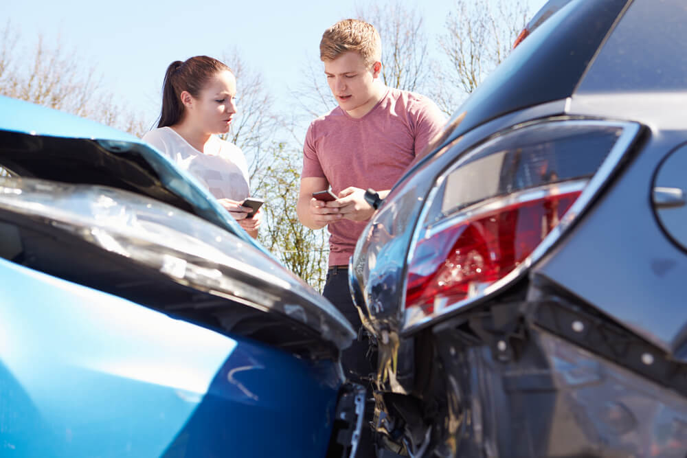 Photograph of man and woman exchanging insurance information after a car crash