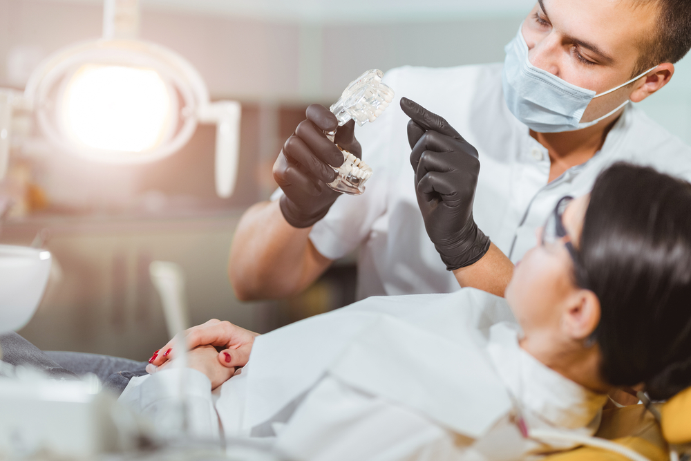 Image of male dentist giving female patient dental treatment in a brightly lit room