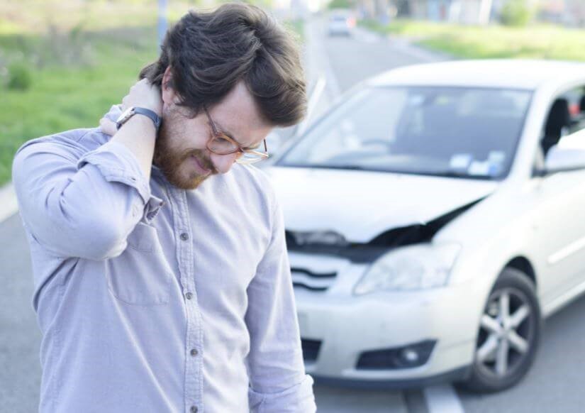 Photograph of man with whiplash after white car road accident