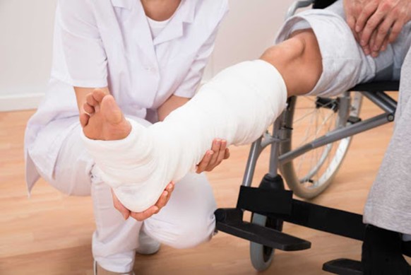 Man in a leg cast and wheelchair receiving compensation for injury and medical assistance