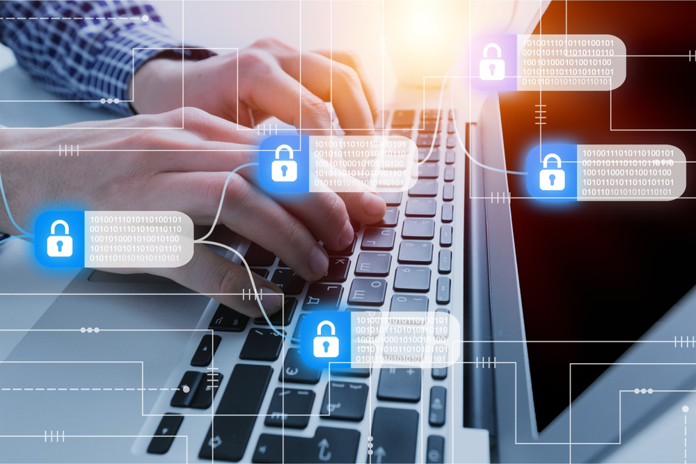 Photograph of man working at laptop with blue padlock icons in the foreground to demonstrate a data breach in blog about can personal data be used without permission.