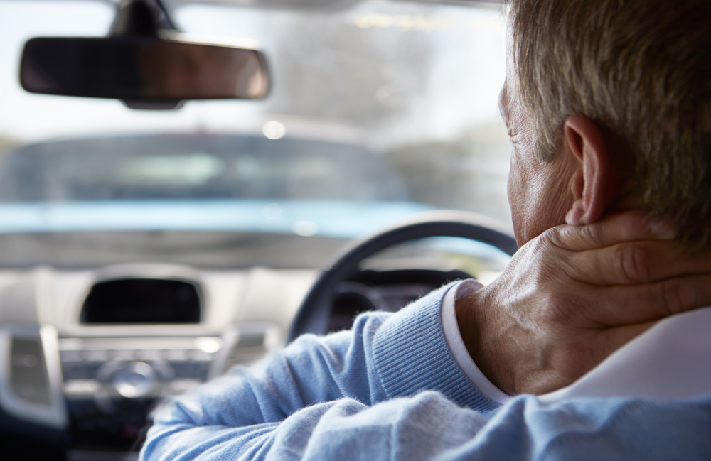 Man in blue shirt sustaining a neck injury after a car accident