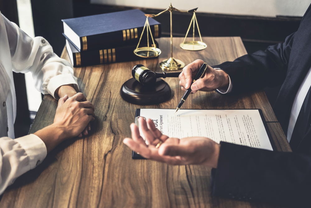 Photograph of solicitor at desk with statue of law and gavel talking to a CICA client