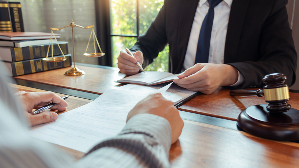 Photograph of a solicitor in suit offering advice to client with various papers and a gavel