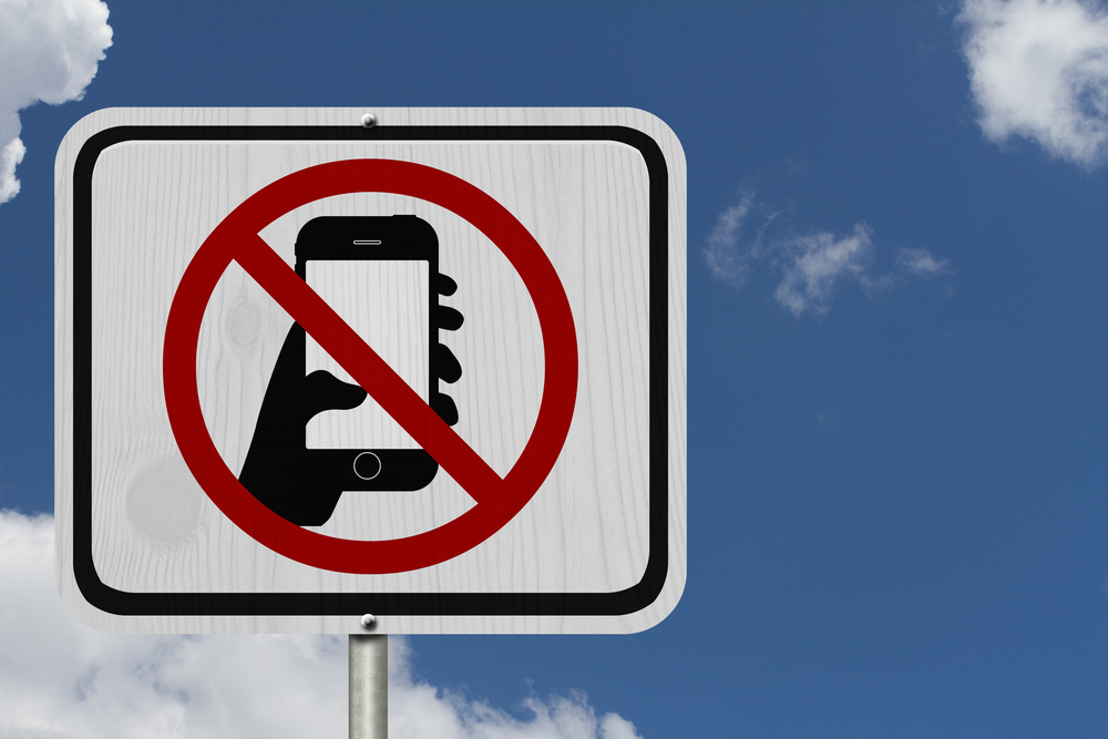 Anti-phone road sign against a bright blue sky with clouds