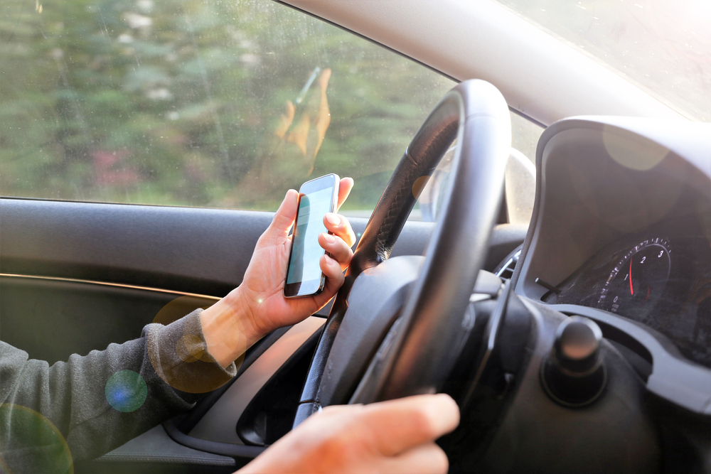 Photograph of man using phone to video call whilst driving