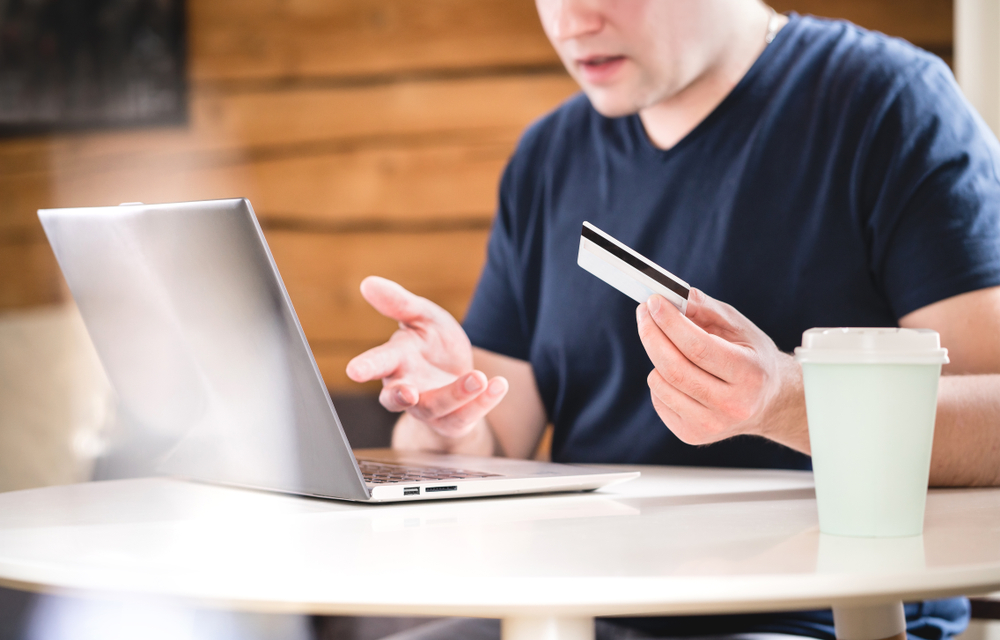 Man filing complaint on his laptop with credit card in his hand