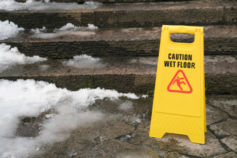 Image of yellow "Caution: Wet Floor" sign on concrete with melted snow