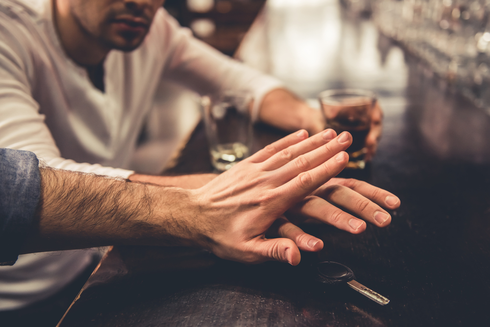 Image of man stopping drunk friend from drink driving