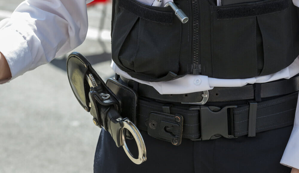 Close up image of a police officers handcuffs attached to his belt