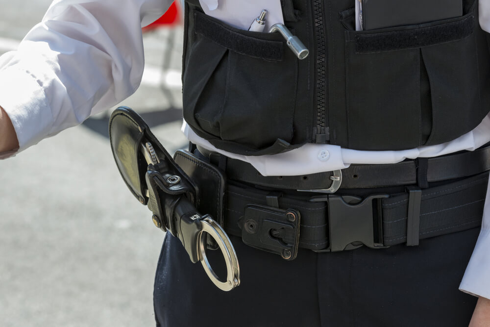 Close up image of a police officers handcuffs attached to his belt