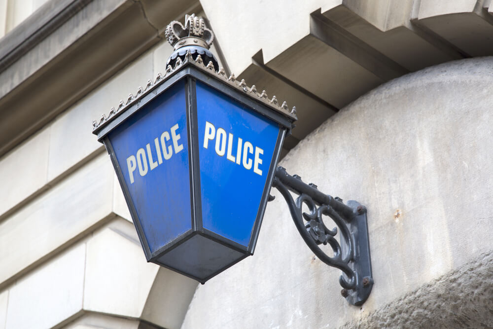 Colour image of a blue police light hung on the wall above a police station