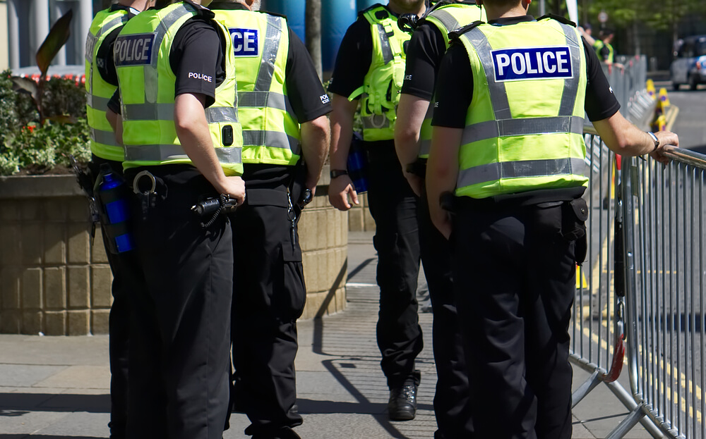 Colour image of six police officers on duty stood on the street policing an event