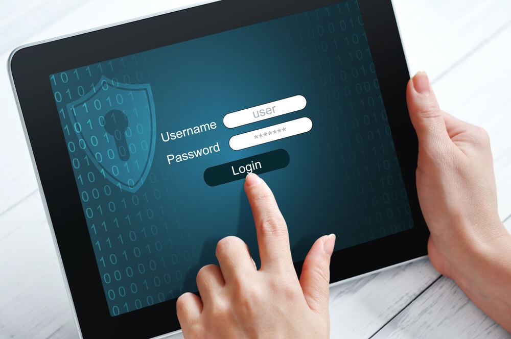 Colour image of someone holding a tablet with a login page on the screen with the text username, password and login