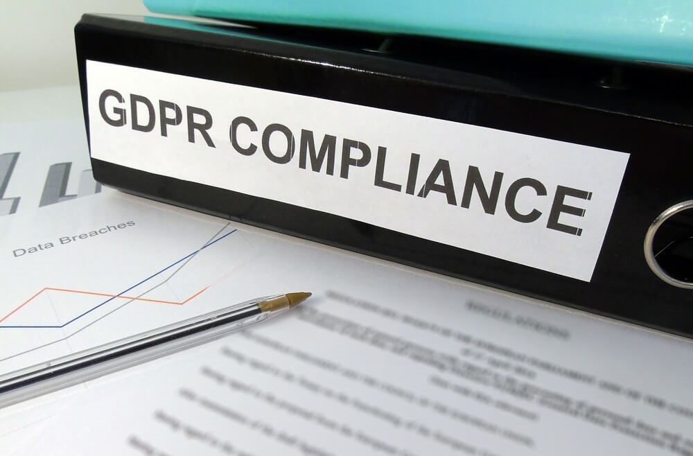Colour image of files saying 'GDPR compliance' on top of paper with information about data breaches and a pen