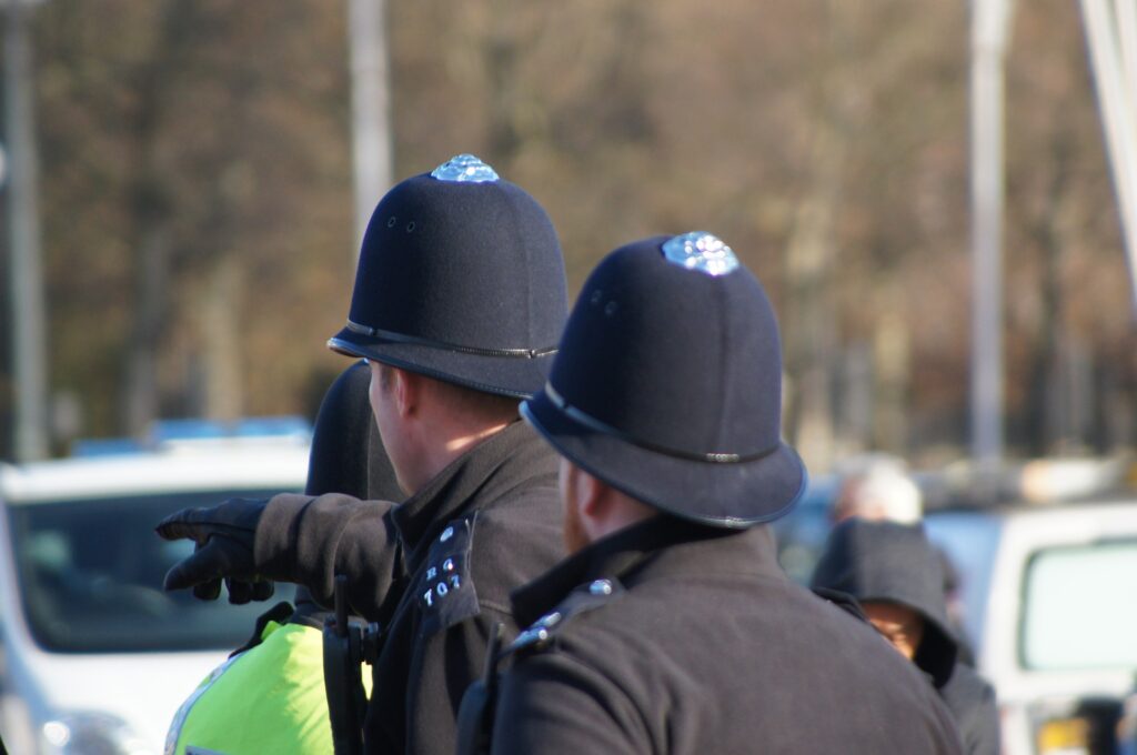 Two police officers in black uniforms and black helmets, seen from behind.