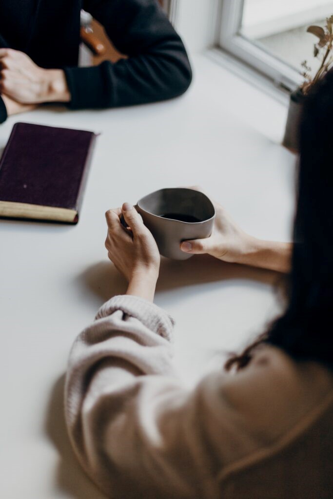 A woman holding a cup on a table getting consulted with victim support. 