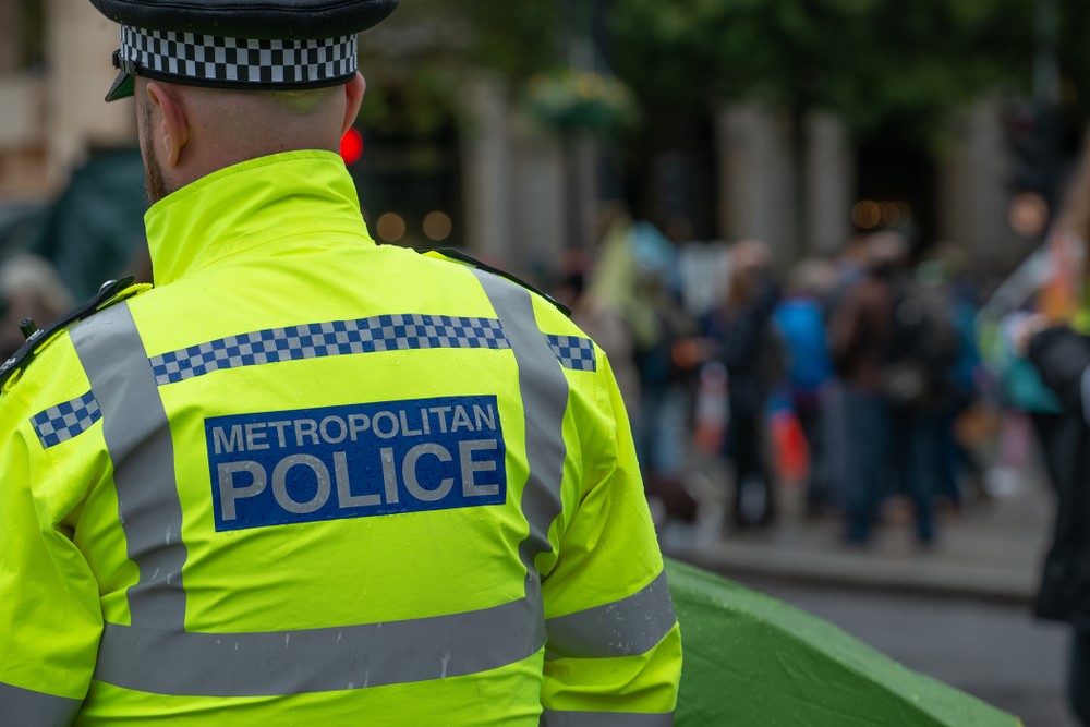 Colour image of a Metropolitan Police Officer with his back to the camera wearing a high-vis police jacket