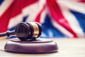 A judges wooden gavel in front of a British flag.
