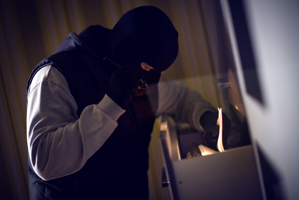 Masked man with torch thumbs through filing cabinet for blog about types of data breaches.