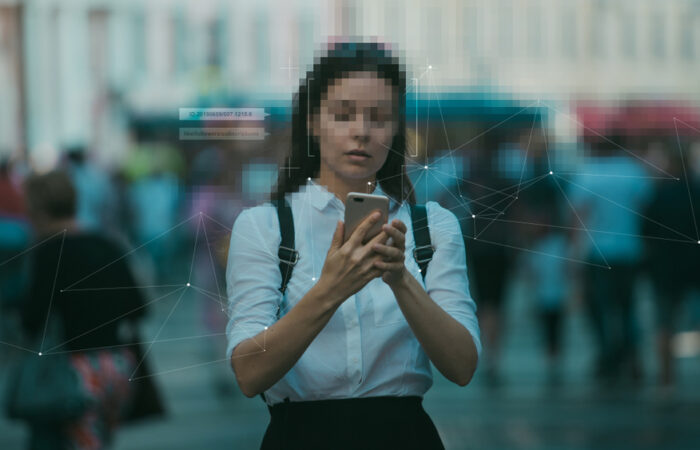 Woman in street looks at her phone with face pixelated for blog about What constitutes misuse of data?