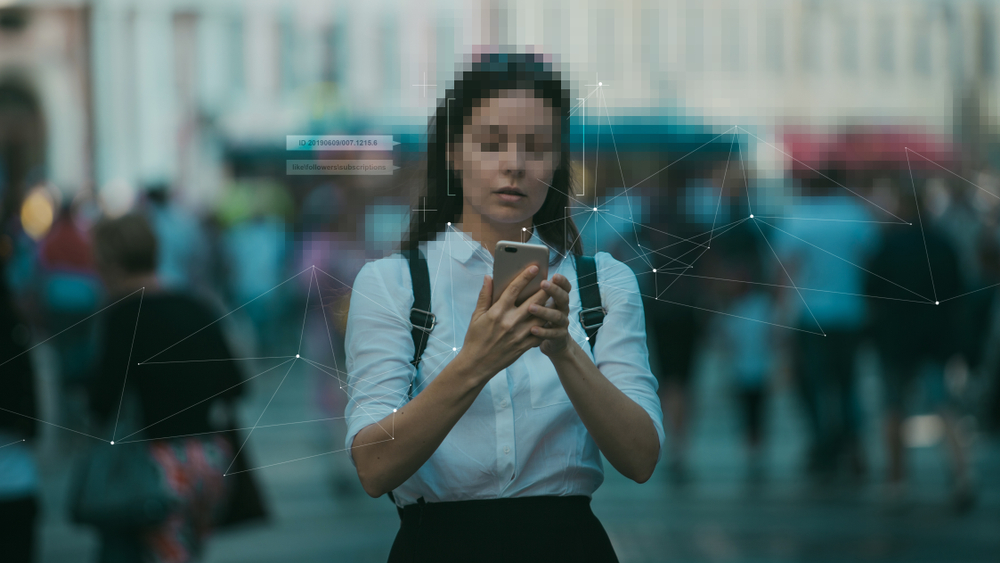 Woman in street looks at her phone with face pixelated for blog about What constitutes misuse of data?