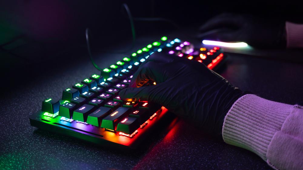 Gloved hands type onto backlit keyboard for blog about types of data breaches.