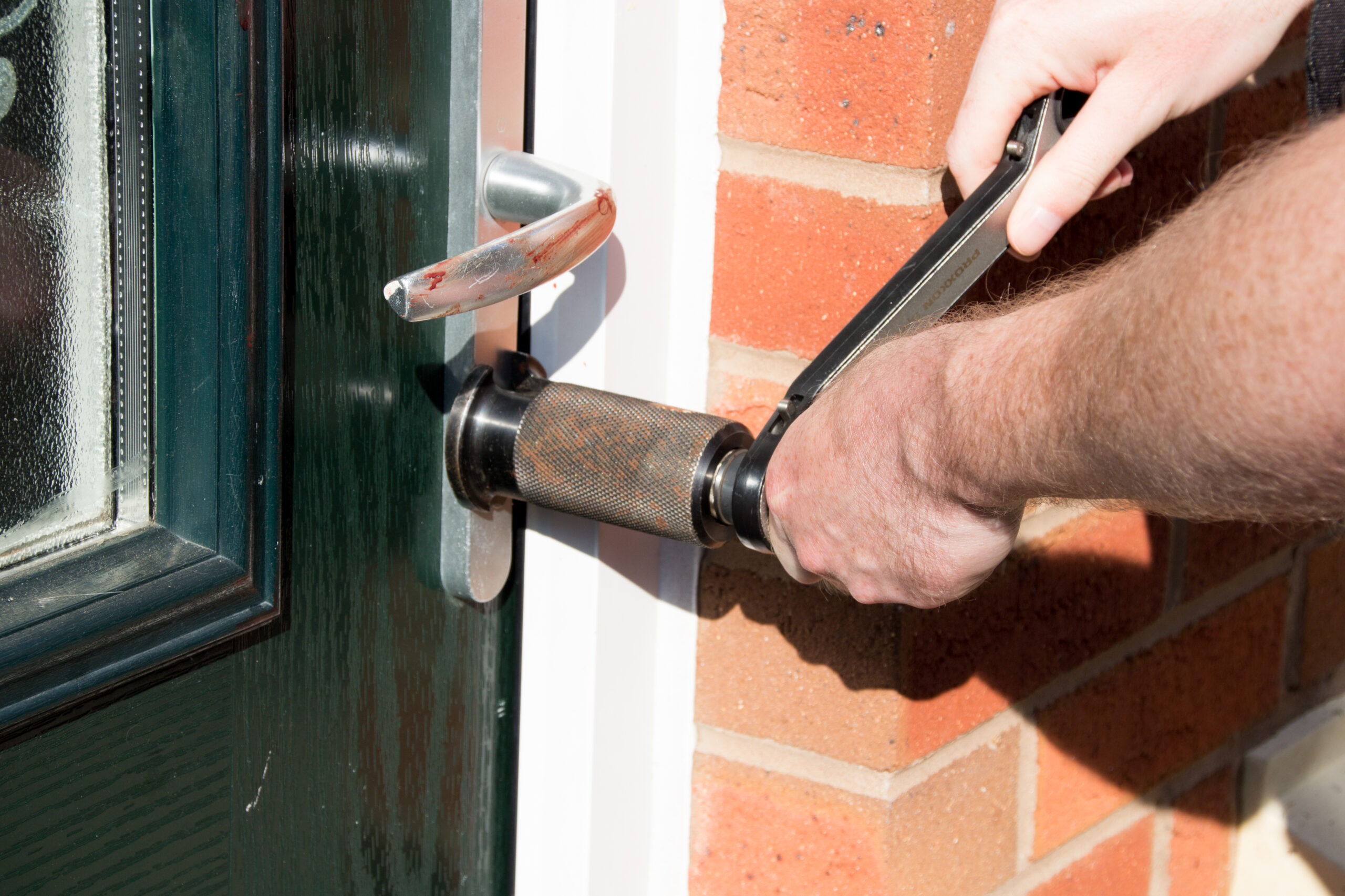 Close shot of police using a lock device to force entry into uk home for blog about compensation for damage caused by police.