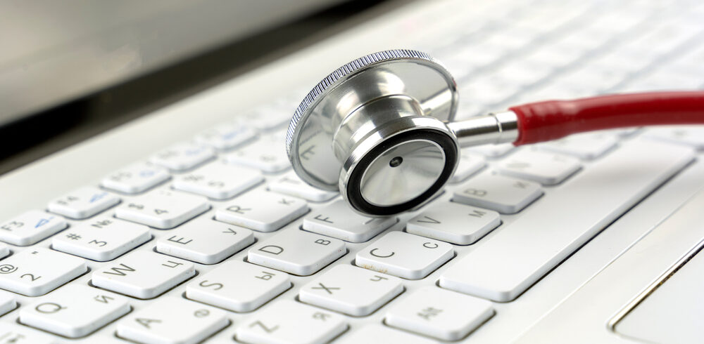medical data breach concept image, a stethoscope lying on a laptop keyboard