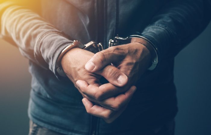 Up close image of a mans hands in cupped together wearing handcuffs